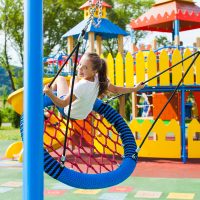 Kid is swinging on the spider web nest swing at the playground